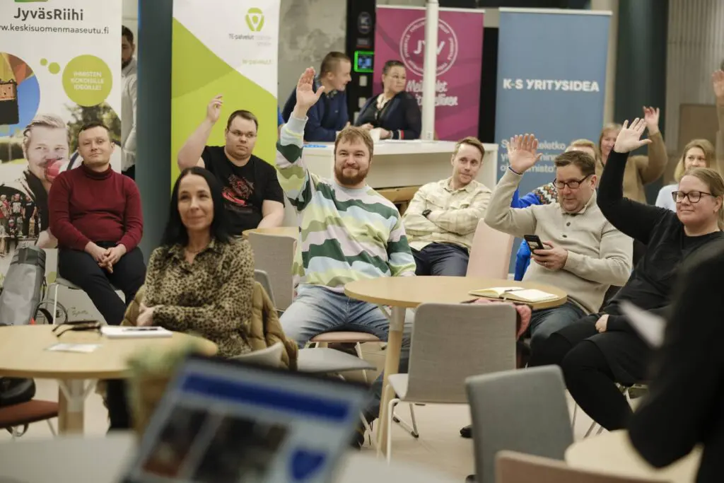 Iloisia ihmisiä viittaamassa tapahtumassa Crazy Town coworking-tiloissa Jyväskylässä