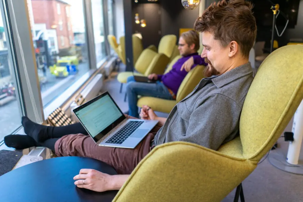 Kasvuyrityksen kaksi työntekijää tekevät töitä rennosti kannettavalla coworking-tilassa