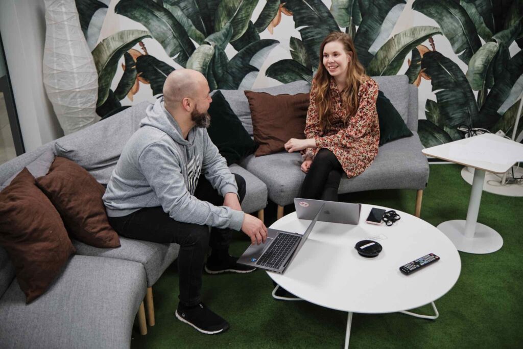 Kaksi ihmistä kokouksessa viidakkotapetin edessä. Kuva Crazy Townin moderneista toimitiloista Jyväskylässä.